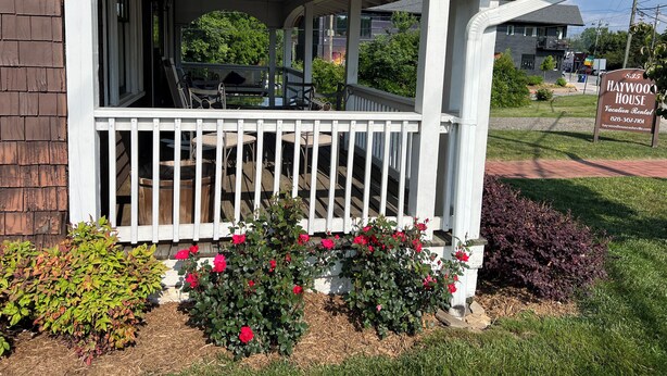 A covered porch with outdoor seating and a sign for Haywood House. - Haywood House: West Asheville's Newly Restored And Most Walkable Rental! (Asheville)