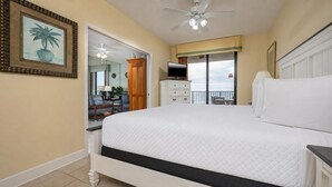 A bedroom with a large bed, a ceiling fan, a TV, and a view of the balcony. - Phoenix X 515 | Gulf-Front Condo Near Flora-Bama in Orange Beach (Orange Beach)