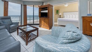 A living room with a sofa, armchair, and coffee table, a TV stand, and a balcony with a view. - Phoenix X 515 | Gulf-Front Condo Near Flora-Bama in Orange Beach (Orange Beach)