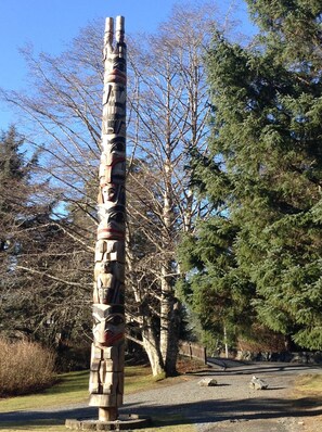 Un totem in un parco con alberi e un sentiero sterrato.