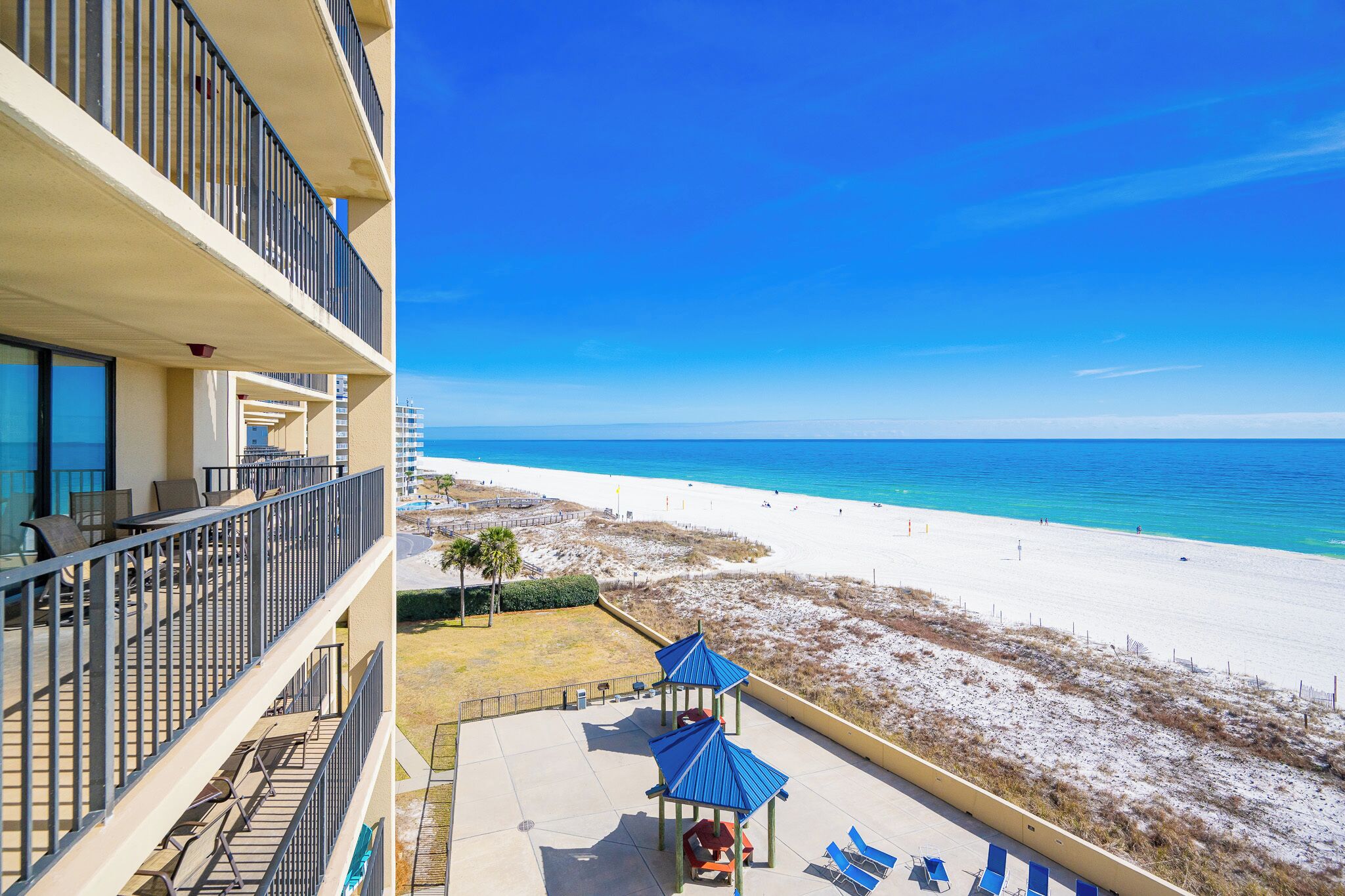 A hotel balcony with a view of a beach and ocean.