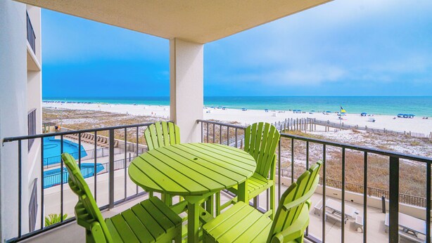 A balcony with a view of a beach and a pool.