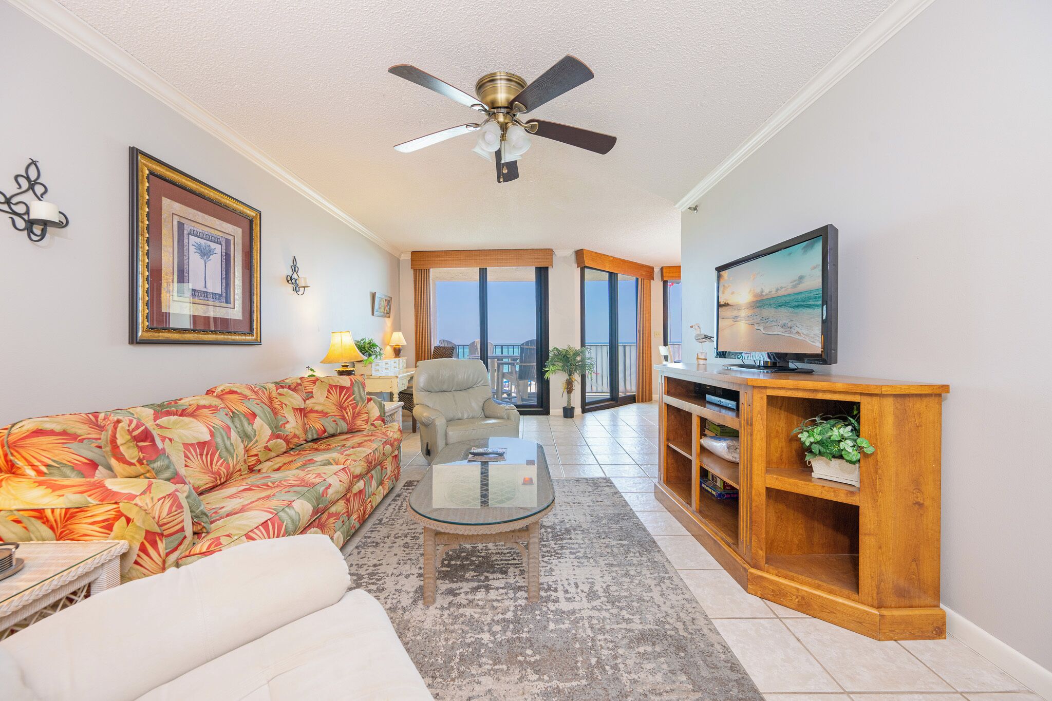A living room with a sofa, coffee table, TV, and a ceiling fan.
