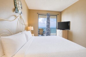 Een hotelkamer met een groot bed, een televisie, een balkon met uitzicht en een decoratief wandobject.