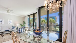 A modern living room with a glass table, comfortable seating, and a view of the cityscape through large windows. - LAZY RIVER, PUTTING GREEN, OH MY! Phoenix on the Bay 1106 (Orange Beach)
