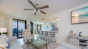 A hotel room with a living area, dining table, chairs, a ceiling fan, a large window, and a view of the ocean. - 2nd FLOOR One Bedroom ~ XTRA HALF BATH! ~ Phoenix 7! (Orange Beach)