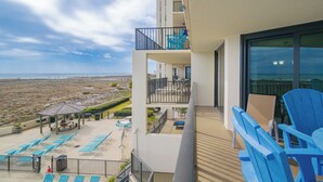 A balcony with a view of the beach, a pool area with lounge chairs, and a building with multiple balconies. - 2nd FLOOR One Bedroom ~ XTRA HALF BATH! ~ Phoenix 7! (Orange Beach)