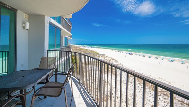 A balcony with a view of a beach, a table, and chairs. - Phoenix IX 505 - Spacious 3BR Gulf Front Unit (Orange Beach)