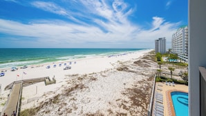 A beach view with a pool, beach umbrellas, and a boardwalk leading to the ocean. - Phoenix IX 505 - Spacious 3BR Gulf Front Unit (Orange Beach)