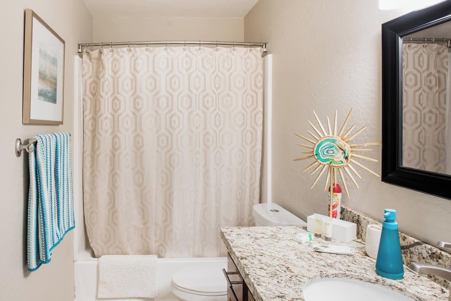 Une salle de bain avec un rideau de douche, des toilettes, un lavabo avec un miroir et un porte-serviettes.