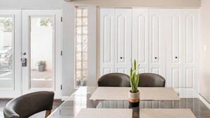 A modern dining area with a glass table, two chairs, and a potted plant. - Architect-Designed Retreat with a BBQ Patio and Pool (Mesa)