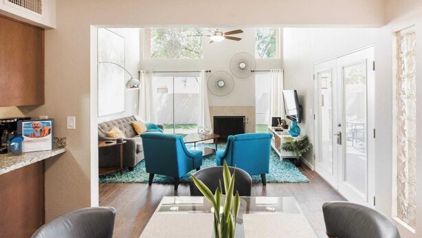 A modern living room with a fireplace, a dining area with a glass table, and a kitchen with a built-in oven. - Architect-Designed Retreat with a BBQ Patio and Pool (Mesa)