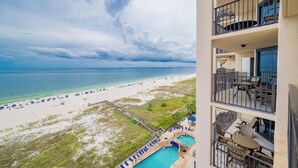 A hotel with a pool, outdoor seating, and a view of the beach and ocean.