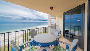 A balcony with a table and chairs overlooking a beach.