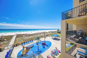 Um resort com área de piscina, cadeiras de espreguiçadeira e vista para a praia.