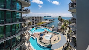 Un hôtel à plusieurs étages doté d’une piscine centrale, d’un espace extérieur aménagé et offrant une vue sur le port de plaisance.