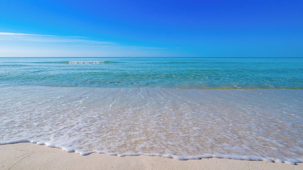 A beach with clear blue water and a sandy shore.