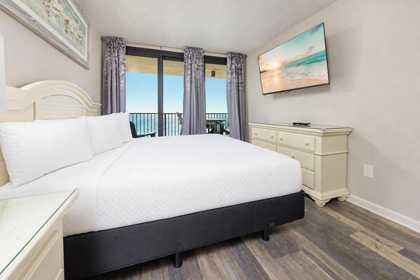 Ein Schlafzimmer mit Bett, Schminktisch, einem Gemälde und Meerblick.