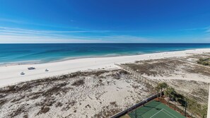 Une vue sur la plage, avec un ciel dégagé, une plage de sable et un court de tennis.
