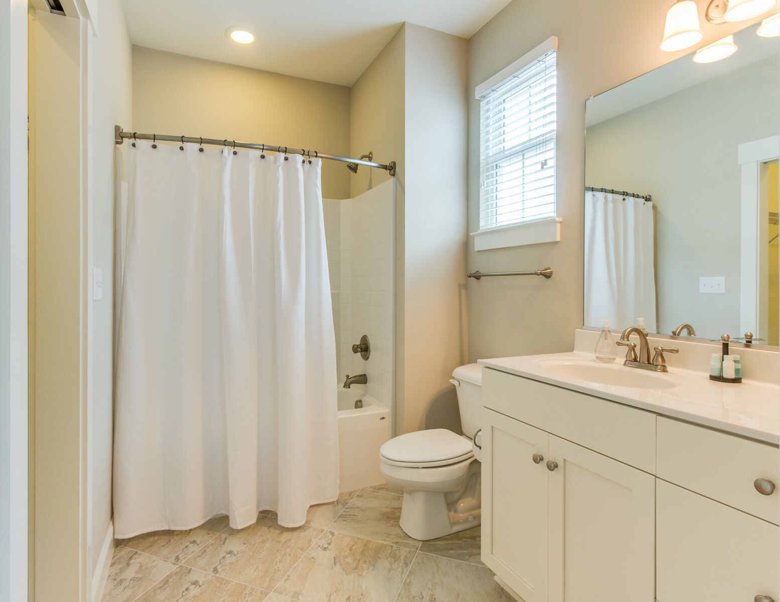 A bathroom with a shower curtain, toilet, sink, and cabinet.