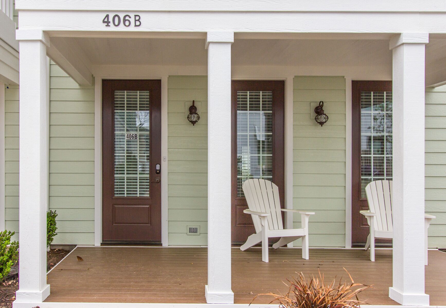 A house with a porch, a door marked 406B, and two white Adirondack chairs.