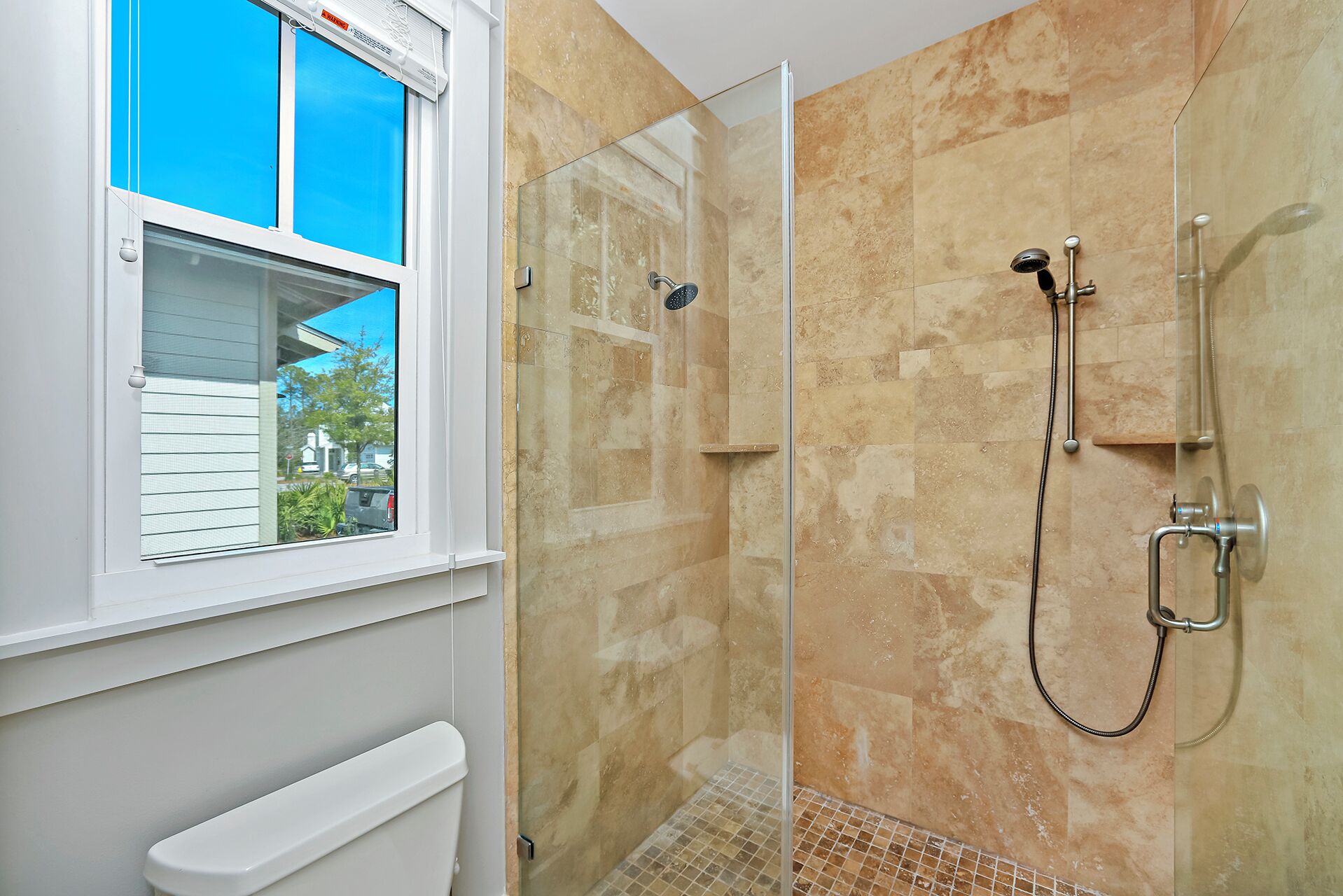 A bathroom with a glass-enclosed shower, a window with blinds, and a white radiator.