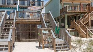 Una escalera de madera que lleva a una casa de playa, con un cartel que dice 'BEACH HOUSE'.