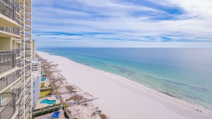 A high-rise hotel with a beach view, including a pool area and a sandy beach.