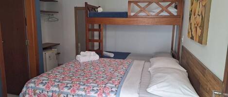 A bunk bed with a floral bedspread, a wooden headboard, and a small shelf with a hanger.