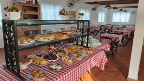 Un bufé con diversos productos de panadería y pastelería, manteles a cuadros y una vitrina de cristal.