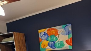 Una cama bien hecha con una colcha a rayas, un cabecero de madera y un cuadro de peces de colores en la pared.