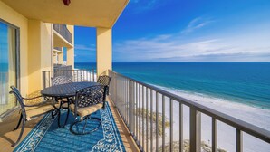 Un balcon avec une table et des chaises, donnant sur une plage.