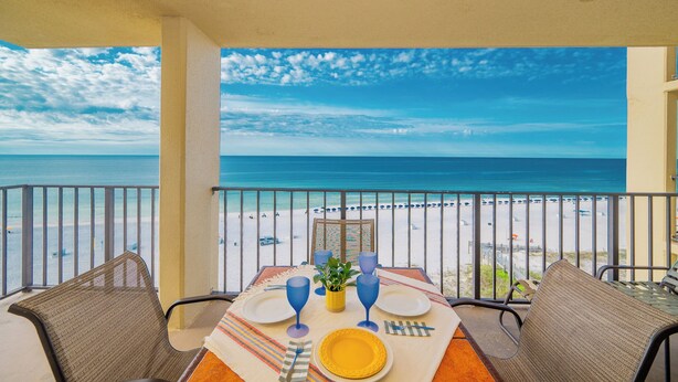 A dining table with chairs and a view of the beach.