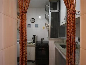 Cozinha compacta com armários brancos, fogão e janela.