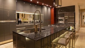 A modern kitchen with a central island, stainless steel appliances, and bar stools.