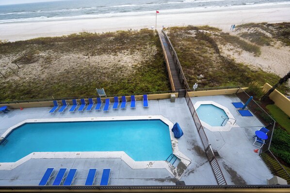 Una piscina en la azotea con sillones de descanso azules, una piscina pequeña y vistas a la playa.