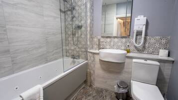 Un baño moderno con bañera, ducha, lavabo, inodoro y espejo.