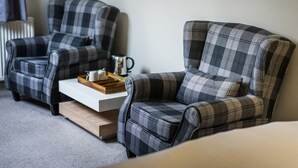 Two plaid armchairs with a tray table, a radiator, and a white table between them. - Ormonde House Hotel (Lyndhurst)