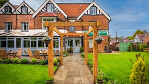 A hotel with a covered patio area, a brick facade, and a well-maintained lawn. - Ormonde House Hotel (Lyndhurst)