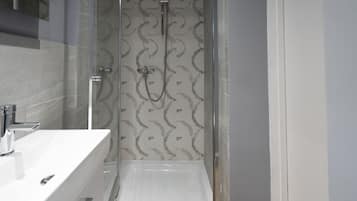 A modern bathroom with a glass-enclosed shower, a white sink, and a patterned tile backsplash.