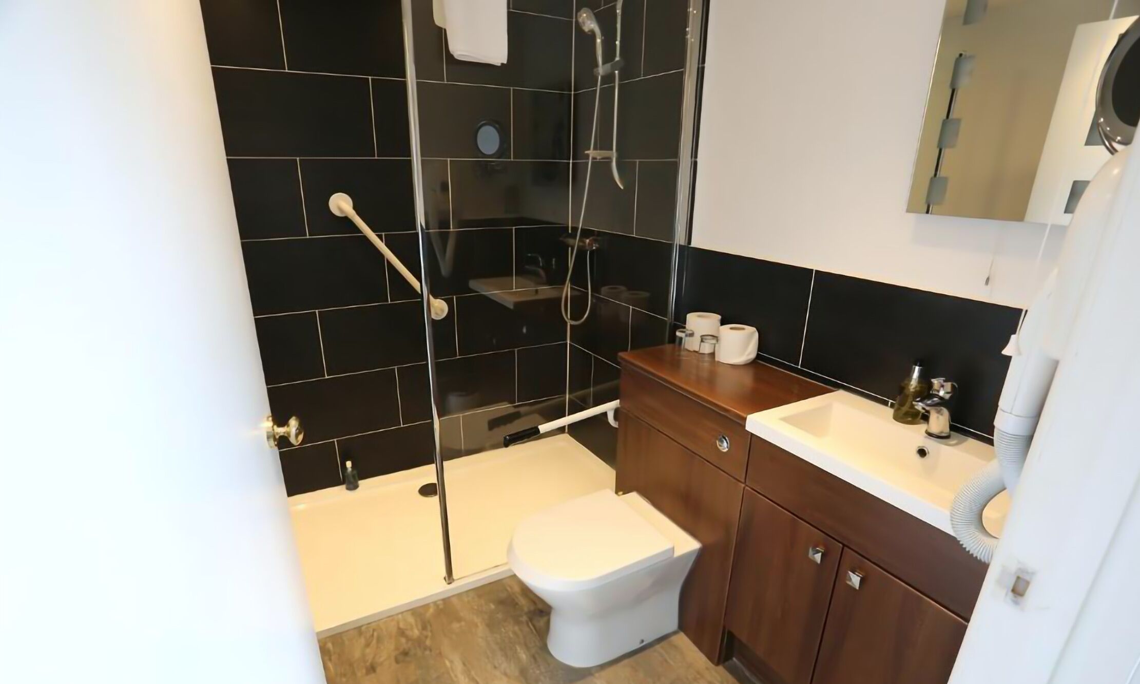A modern bathroom with a glass-enclosed shower, a white toilet, and a wooden vanity with a sink.