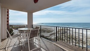 A balcony with a table and chairs, overlooking a beach with a railing. - Phoenix East II 2043 | Gulf-Front 3BR Beach Retreat (Orange Beach)
