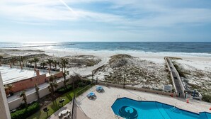A beach view from a hotel balcony with a swimming pool and lounge chairs. - Phoenix East II 2043 | Gulf-Front 3BR Beach Retreat (Orange Beach)