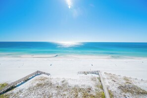 Una playa con un paseo marítimo de madera que conduce a la orilla, agua turquesa cristalina y una playa de arena.