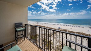 Een balkon met uitzicht op een strand, met een stoel en een tafel.