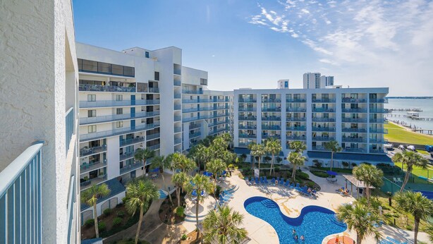 A hotel with multiple balconies, a swimming pool, and a view of the sea.
