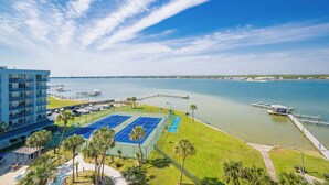 A hotel with a tennis court, a dock, and a view of the water.