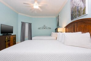 Habitación de hotel con cama, televisión, ventilador de techo y un cuadro en la pared.