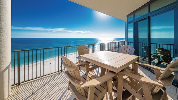 A balcony with a wooden table and chairs, overlooking a beach and the ocean. - The Oasis of Orange Beach 1003 (Orange Beach)