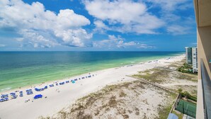A beach view with clear skies, a sandy shore, and a few umbrellas. - Beachfront Fun & Nightlife Phoenix X 1406 (Orange Beach)